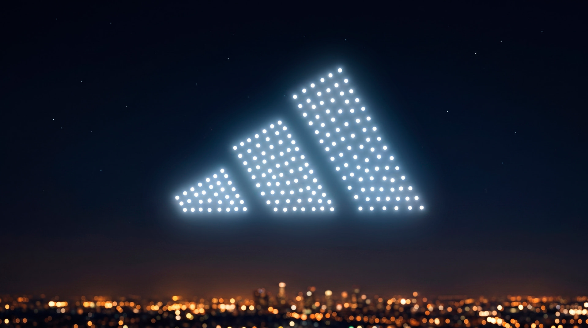 Logo de Adidas formado por drones blancos sobre la ciudad de noche