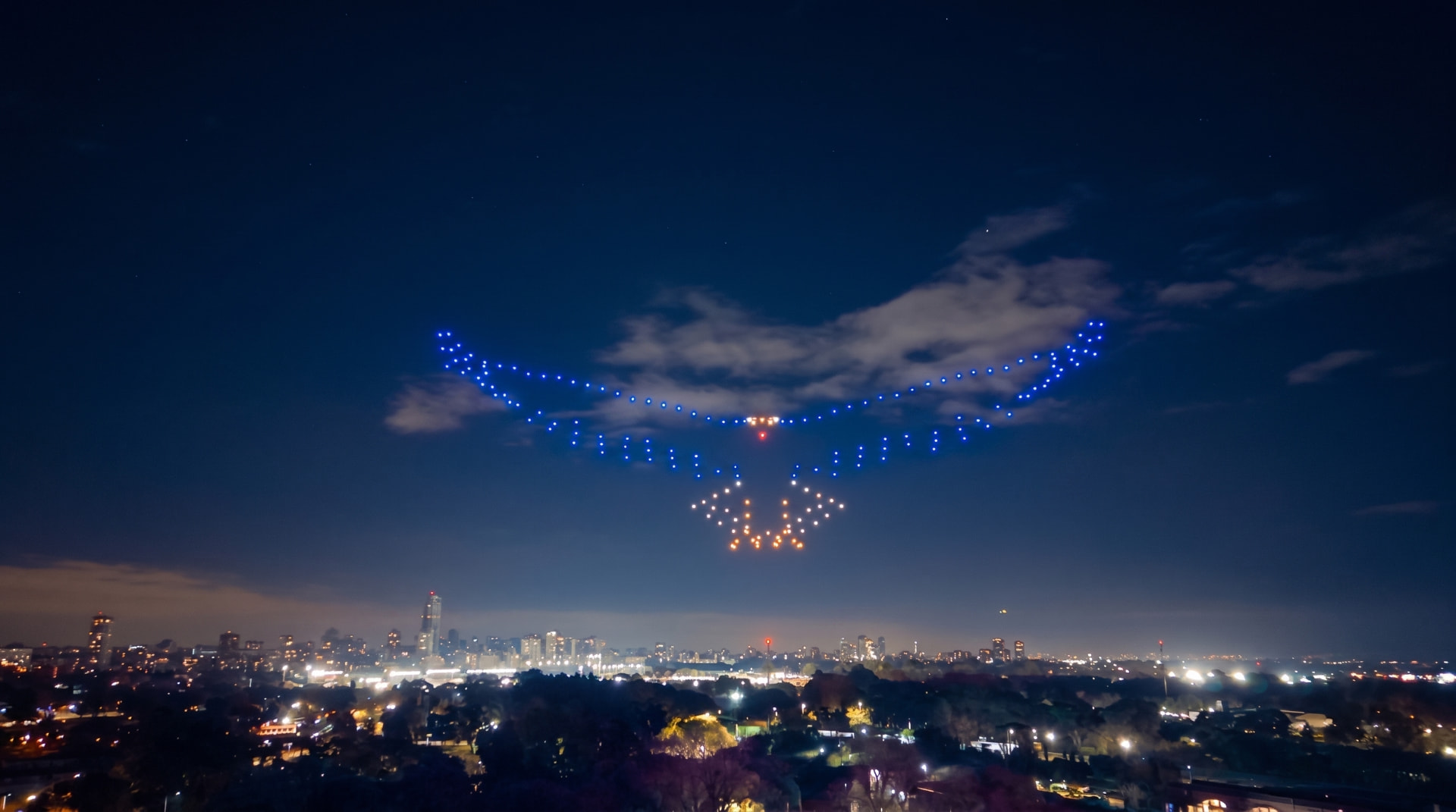 Águila azul formada por drones sobrevolando la ciudad de noche