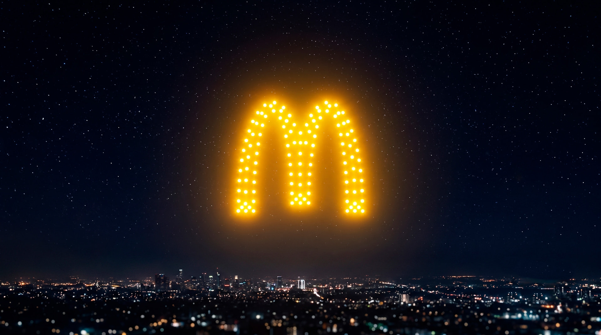 Arcos de McDonald's formados por drones amarillos en el cielo estrellado