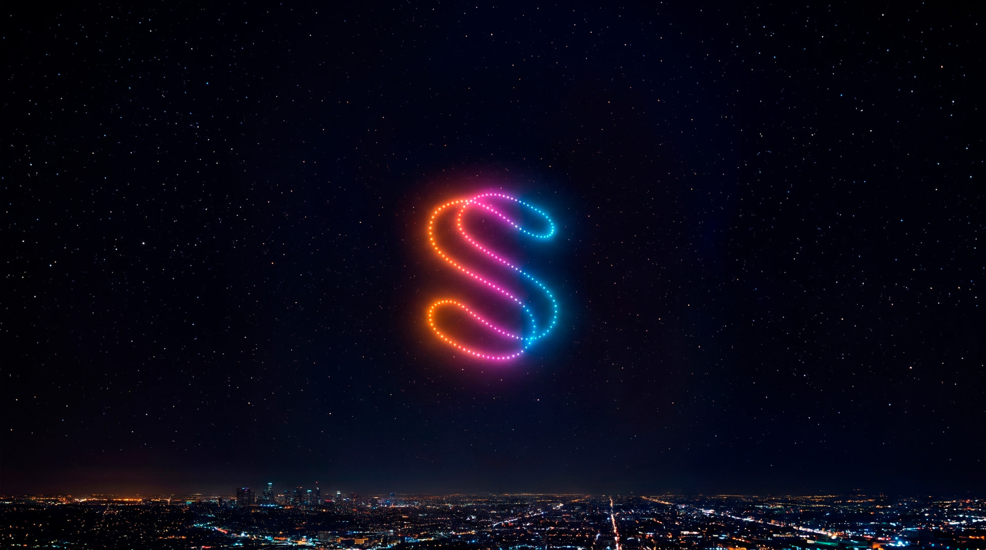 Isologo de Singular Stories formado por drones de colores sobre la ciudad