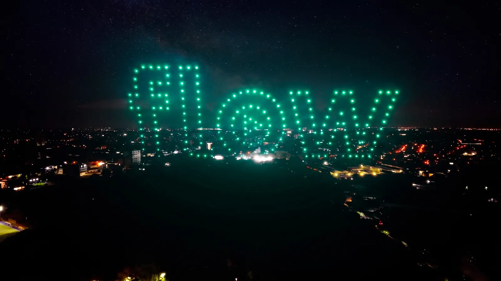 Logo de Flow formado por drones verdes sobre la ciudad durante el show de María Becerra